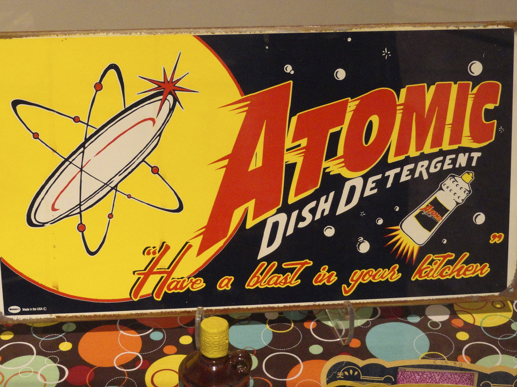 Advertisement for Atomic Dish detergent featuring an atom and bottle designed to resemble ar rocketship